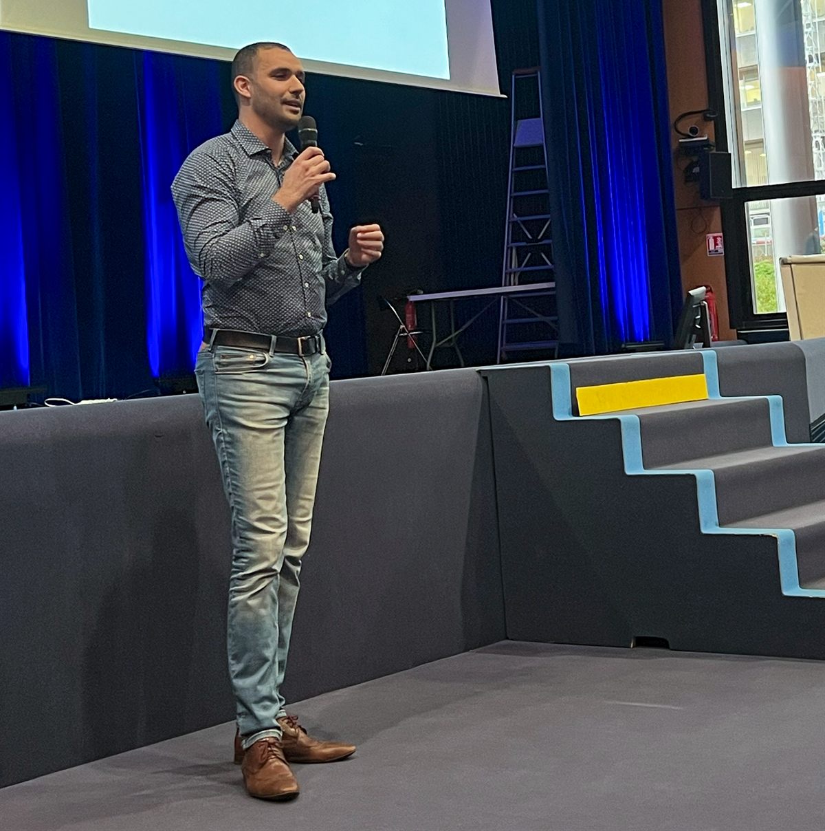 Adel Assakkour sur scène, micro en main, lors d'une intervention devant des managers